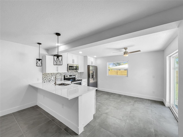 kitchen with stainless steel appliances, light countertops, backsplash, a sink, and baseboards