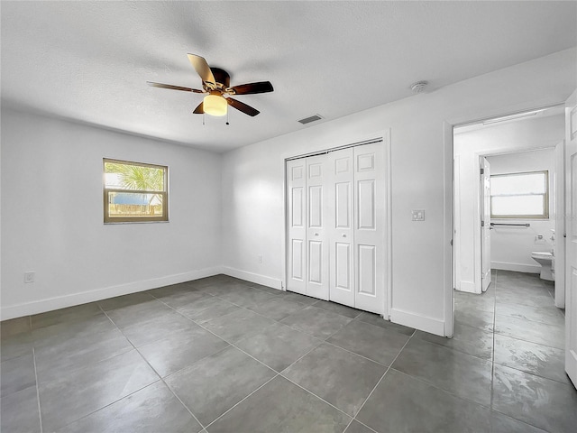 unfurnished bedroom with ceiling fan, tile patterned floors, and multiple windows