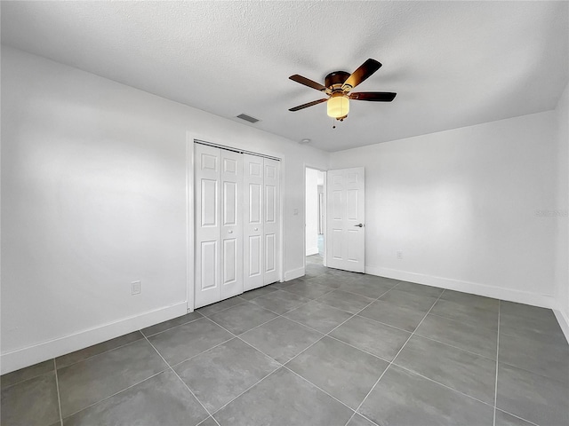 unfurnished bedroom featuring ceiling fan, a closet, tile patterned flooring, and a textured ceiling