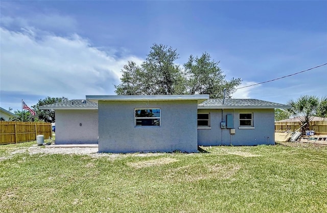 back of property with a yard, stucco siding, and fence