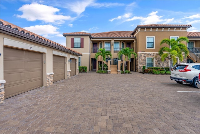 mediterranean / spanish-style home with stone siding, stucco siding, community garages, and stairs