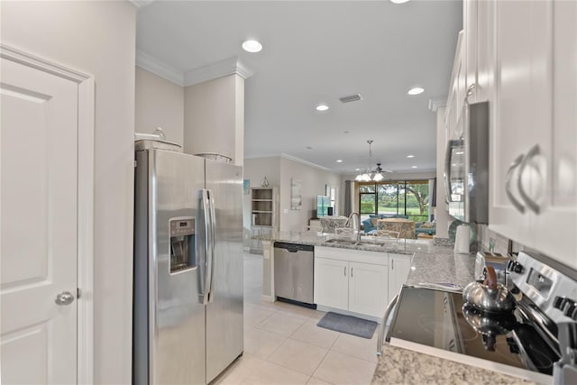 kitchen featuring appliances with stainless steel finishes, a peninsula, light stone countertops, white cabinetry, and a sink