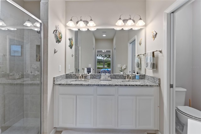 bathroom with double sink vanity, a shower with door, and toilet