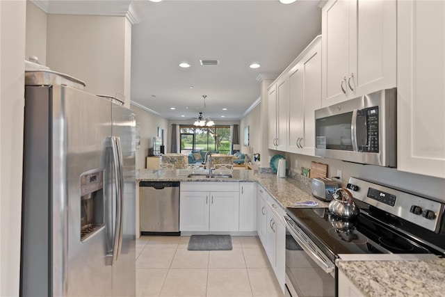 kitchen with stainless steel appliances, ornamental molding, a peninsula, and white cabinets