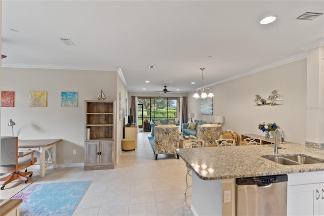 kitchen featuring light stone counters, open floor plan, stainless steel dishwasher, white cabinetry, and a sink