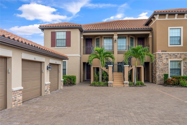 mediterranean / spanish-style house featuring stone siding, a tiled roof, and stucco siding