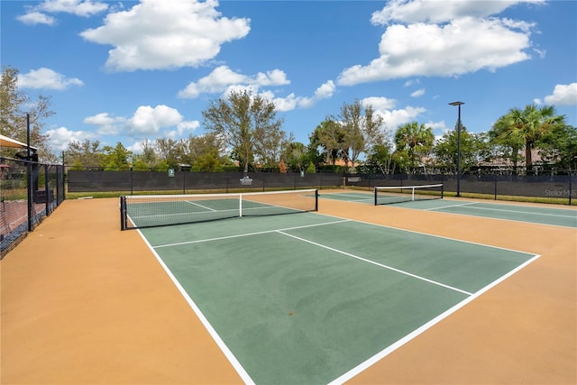 view of tennis court with community basketball court and fence