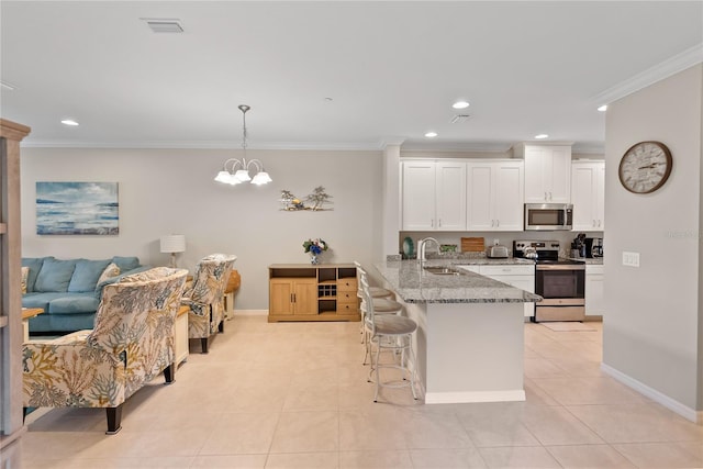 kitchen with light stone counters, a sink, white cabinetry, appliances with stainless steel finishes, and pendant lighting