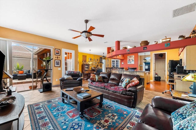 tiled living room featuring ceiling fan with notable chandelier