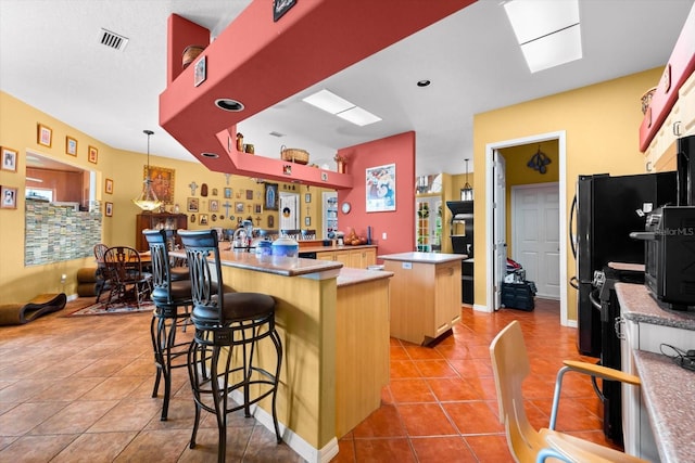 kitchen with a breakfast bar, a center island, hanging light fixtures, light tile patterned flooring, and kitchen peninsula