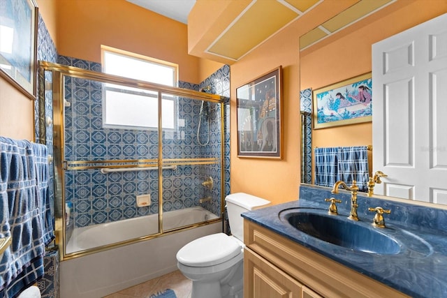 full bathroom with toilet, vanity, tile patterned floors, and bath / shower combo with glass door