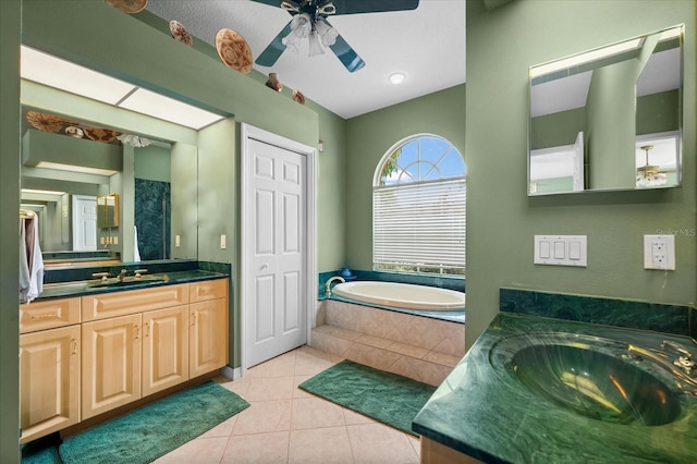 bathroom with tile patterned flooring, vanity, ceiling fan, and tiled bath