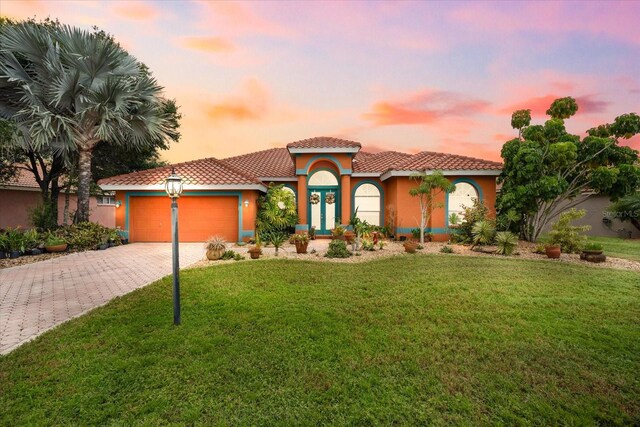 mediterranean / spanish house with a lawn and a garage