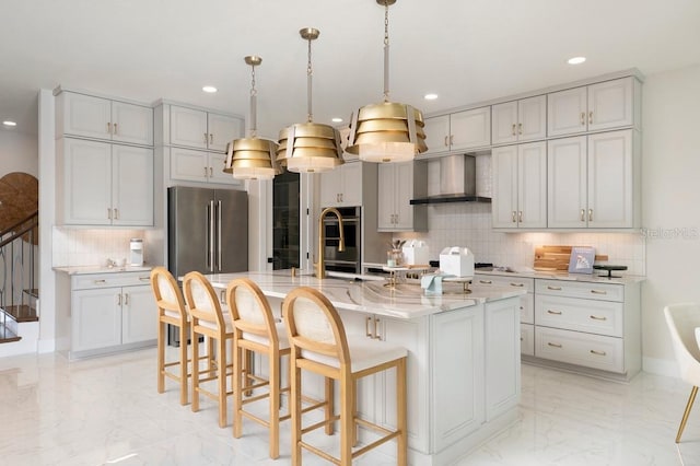 kitchen featuring high end refrigerator, tasteful backsplash, light tile patterned floors, a center island with sink, and wall chimney range hood