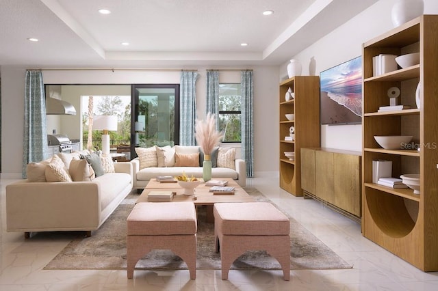 living room with a raised ceiling, a healthy amount of sunlight, and light tile patterned floors