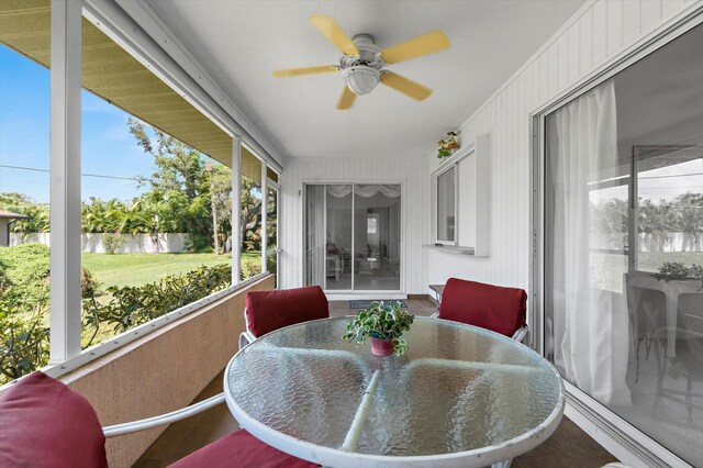 sunroom / solarium featuring a wealth of natural light, ceiling fan, and a water view