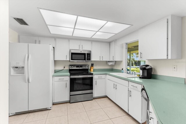 kitchen with sink, light tile patterned floors, appliances with stainless steel finishes, and white cabinets