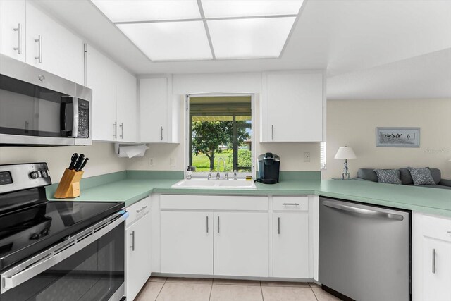 kitchen with white cabinets, light tile patterned floors, stainless steel appliances, and sink