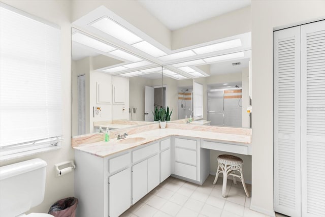 bathroom with vanity, toilet, a shower with shower door, and tile patterned flooring