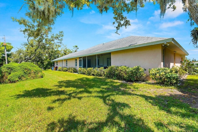 back of property featuring a lawn and stucco siding