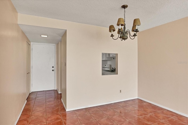 tiled spare room featuring an inviting chandelier and a textured ceiling