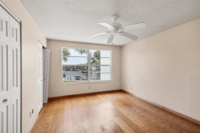 unfurnished bedroom with ceiling fan, a textured ceiling, and light hardwood / wood-style floors