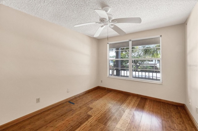 spare room with ceiling fan, a textured ceiling, and wood-type flooring