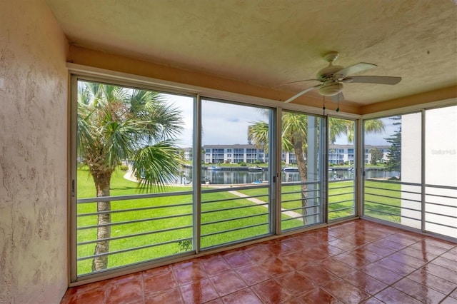 unfurnished sunroom featuring ceiling fan and a water view