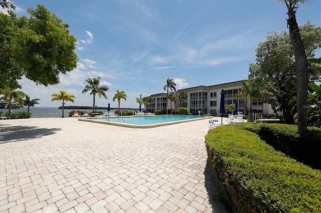 view of pool with a water view and a patio area