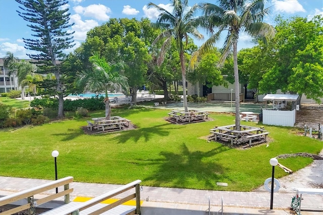 view of community featuring a lawn, a pool, and an outdoor fire pit