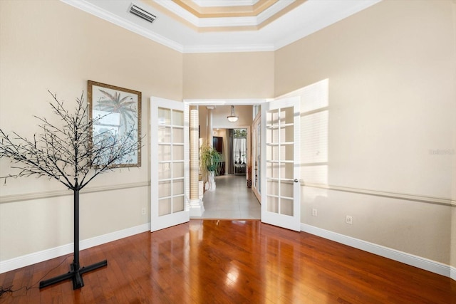 spare room with ornamental molding, wood-type flooring, french doors, and a tray ceiling