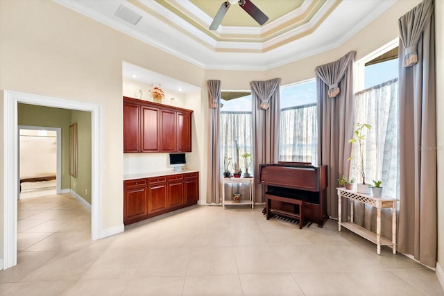 sitting room with a raised ceiling, light tile patterned floors, ceiling fan, and ornamental molding