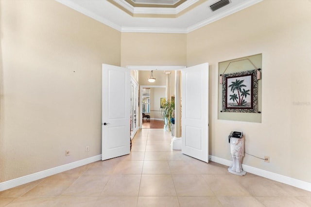 hall featuring crown molding, a raised ceiling, and light tile patterned floors