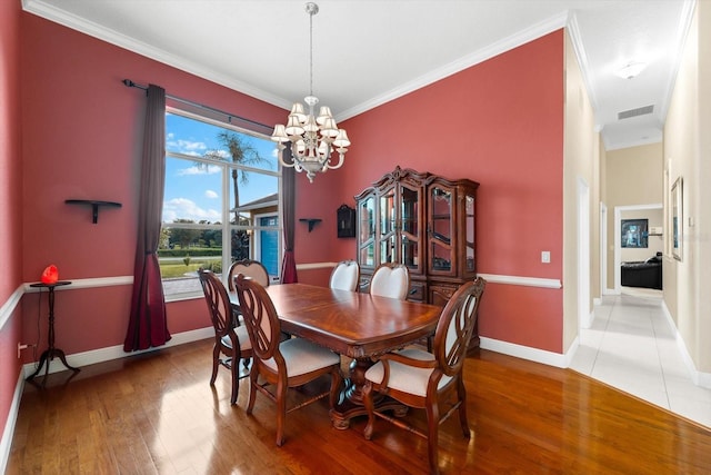 dining area featuring hardwood / wood-style flooring, crown molding, and a chandelier