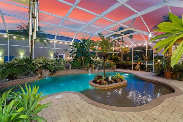 pool at dusk featuring a patio area, pool water feature, and glass enclosure