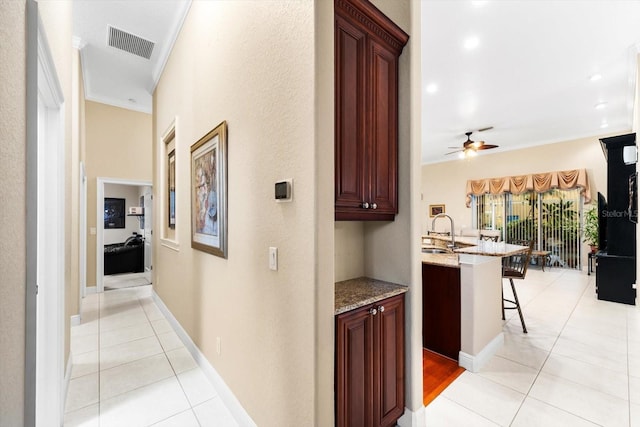 hallway featuring light tile patterned flooring, crown molding, and sink