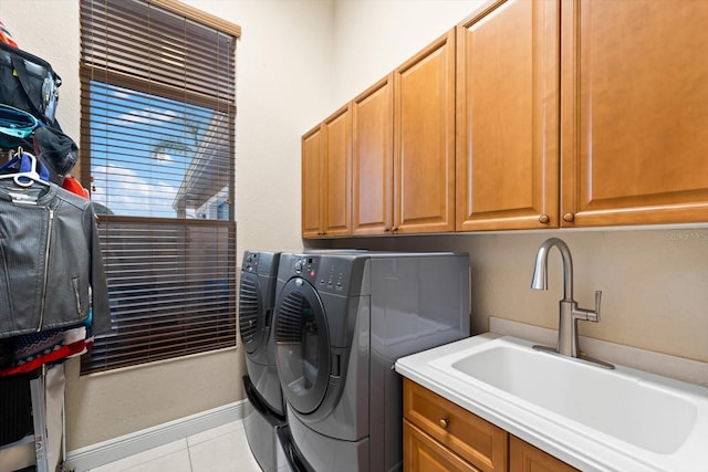 washroom featuring sink, washing machine and dryer, light tile patterned floors, and cabinets