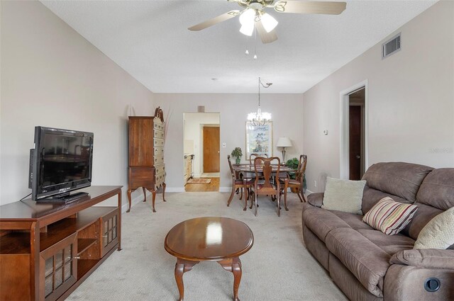 carpeted living room featuring ceiling fan with notable chandelier