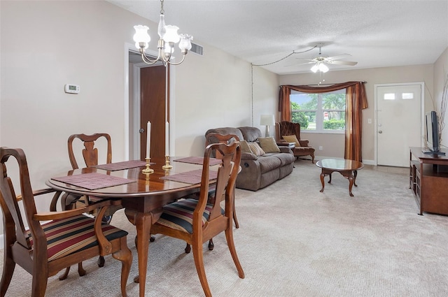 carpeted dining space featuring a textured ceiling and ceiling fan with notable chandelier