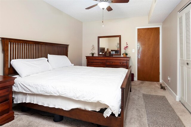 bedroom featuring ceiling fan, light carpet, a closet, and a textured ceiling