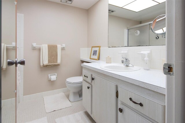 bathroom with tile patterned flooring, toilet, decorative backsplash, and vanity