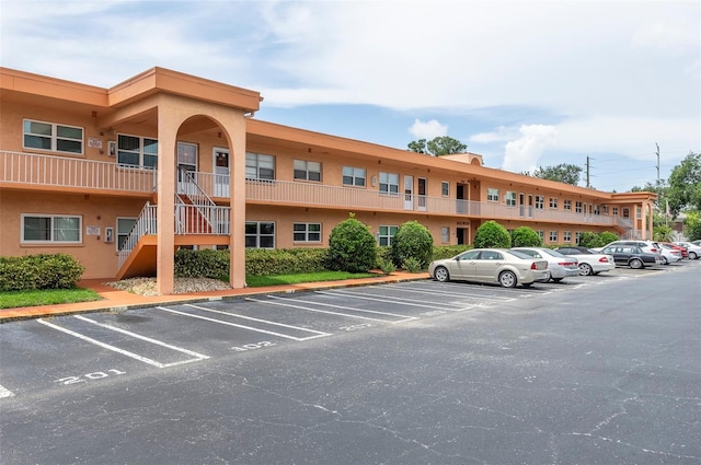 view of building exterior featuring uncovered parking and stairs