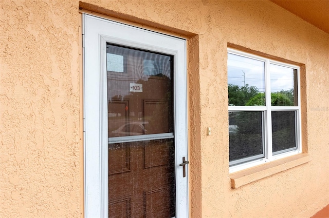 doorway to property featuring stucco siding