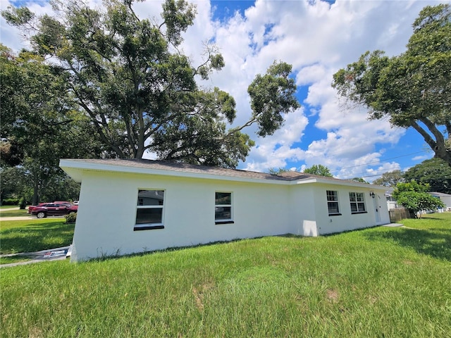 view of side of home featuring a lawn and stucco siding