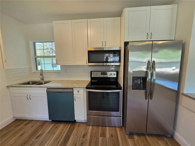 kitchen with light hardwood / wood-style floors, appliances with stainless steel finishes, backsplash, and white cabinets