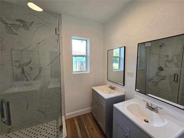 bathroom featuring dual bowl vanity, a shower with door, and wood-type flooring