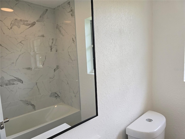 bathroom featuring tiled shower / bath and toilet