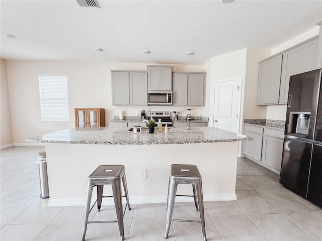 10827 Charlotte Dr, Parrish, FL 34219 - kitchen featuring appliances with stainless steel finishes, gray cabinets, a breakfast bar area, and a kitchen island with sink