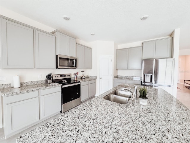 10827 Charlotte Dr, Parrish, FL 34219 - kitchen with stainless steel appliances, gray cabinetry, a sink, and light stone counters