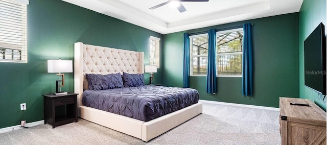 carpeted bedroom featuring ceiling fan and a tray ceiling